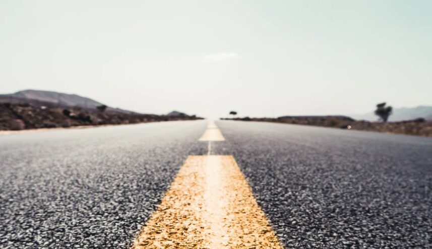 In a barren landscape immersed in gray, the view from the middle of the road and almost at the level of the road surface itself points to the intensely yellow median strips along the way into the unknown expanse, but on a straight line towards the intended destination.